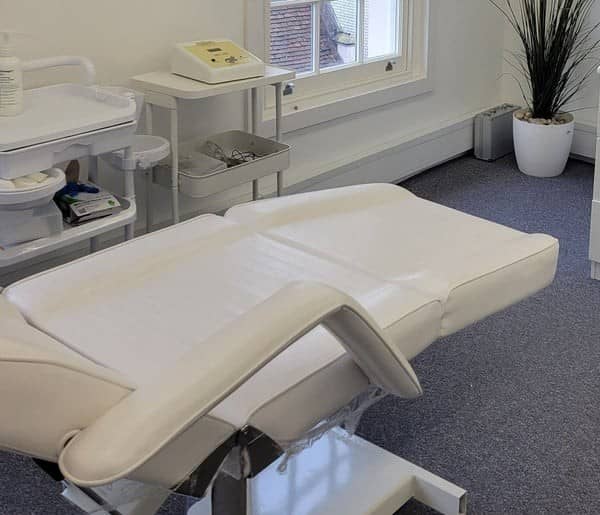 A calm treatment room with a white treatment chair, a tall plant and a sash window A calm treatment room with a white treatment chair, a tall plant and a sash window
